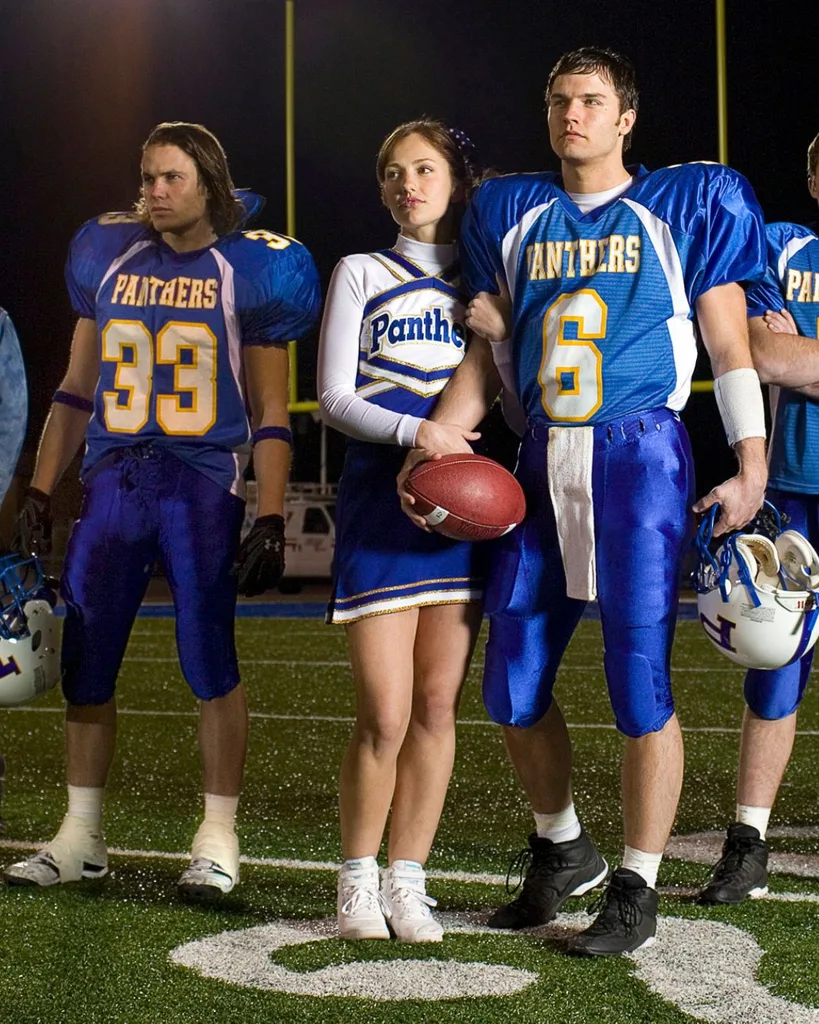 A group of men and women wearing football uniforms standing on a field.
